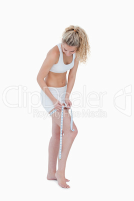 Young blonde woman measuring her thigh in underwear