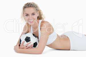 Smiling teenager lying down with a football in her arms