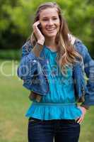 Smiling teenage girl talking on the phone while standing in a pa