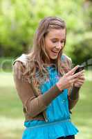 Happy teenage girl receiving a text on her cellphone while stand