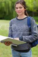 Young relaxed girl holding her notebook while carrying her backp