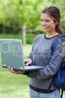 Happy student looking at the screen of her laptop while standing