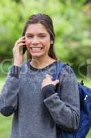 Young smiling woman talking on the phone while standing up in a