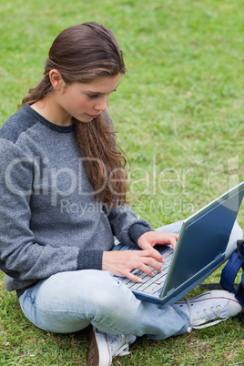 Serious young girl typing on her laptop while looking at the scr