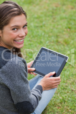 Young girl using her tablet pc while sitting down and showing a