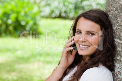 Young smiling woman talking on the phone while looking at the ca