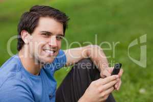 Happy young man looking at the camera while sending a text