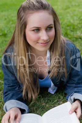 Young smiling girl looking towards the side while lying on the g