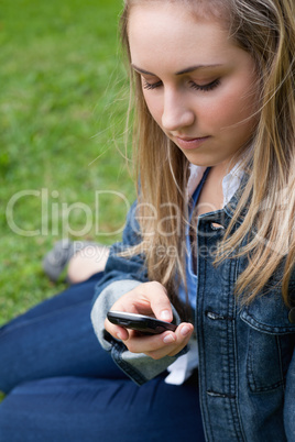 Young girl sending a text while sitting on the grass