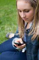 Young girl sending a text while sitting on the grass
