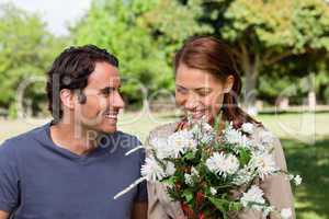 Woman happily looking into a bunch flowers as she is being watch