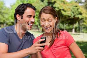 Man laughing as he shows something on his phone to his friend