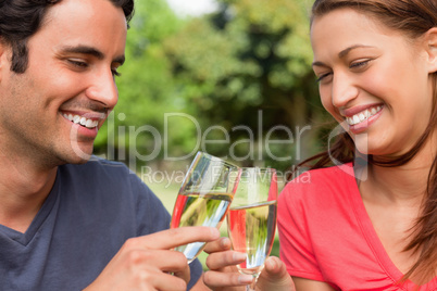 Two friends smiling as they touch glasses of champagne together