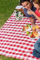 Woman putting food into her friends mouth as they lie on a blank