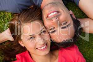 Close-up of two friends looking upwards while lying head to shou