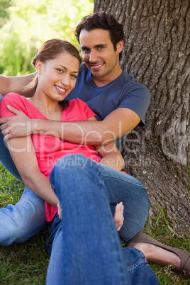 Man looking ahead as he holds her while they sit together in the