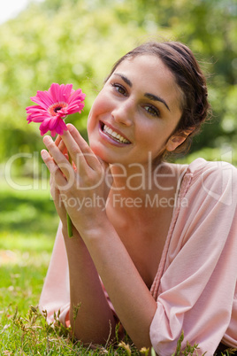 Woman restling her chin on her hands while holding a flower