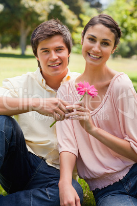 Man giving a flower to a woman as they both look ahead