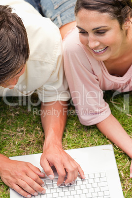 Two friends smiling while lying down as they use the laptop