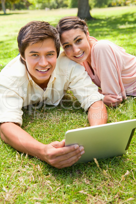 Two friends looking ahead as they use a tablet together