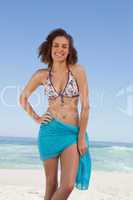 Smiling young woman wearing a blue sarong in front of the sea