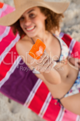 Orange ice lolly held by a young woman while already bitten