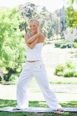 Smiling woman doing stretches in the park