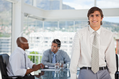 Smiling young businessman leans on table