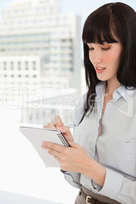 A woman writing down some notes on her note pad