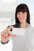 Focus on the business card with a woman holding it