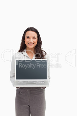 Smiling brunette standing while showing a laptop screen