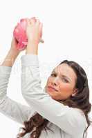 Portrait of a brunette holding an empty piggy bank