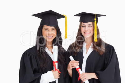 Two friends stand together after graduating