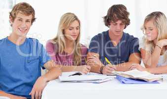 Four friends sitting at the table and studying