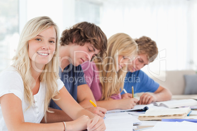 Students working as one girl smiles and looks at the camera
