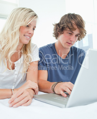 A smiling couple sitting and using the laptop