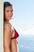Sensual woman in bikini leaning against a wall