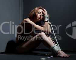 scared naked woman bind with rope in corner