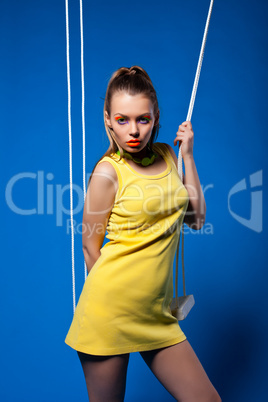 Sexy woman in yellow on swing with bright make-up