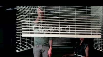 Young couple behind  venetian blinds