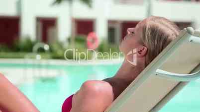 Woman sunbathing on sunlounger at poolside