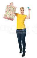Excited teenager holding shopping bag and card