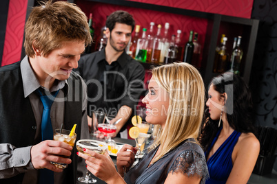 Happy friends at cocktail bar enjoy drinks