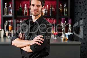 Barman in black standing at cocktail bar