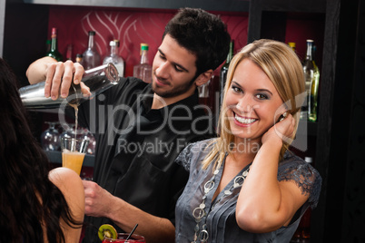 Attractive blond girl at cocktail bar smiling