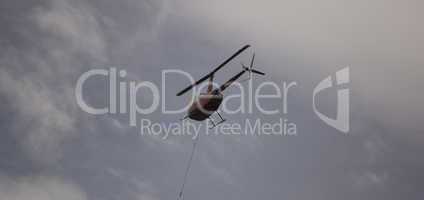 Helicoptor with a water bucket fighting fire