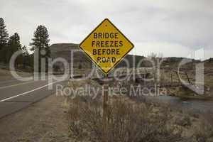 bridge freezes before road sign next to river