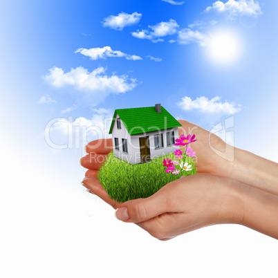 House and human hand against blue sky