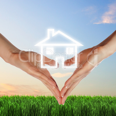 House and human hand against blue sky