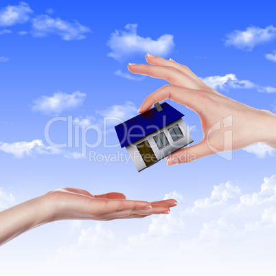 House and human hand against blue sky